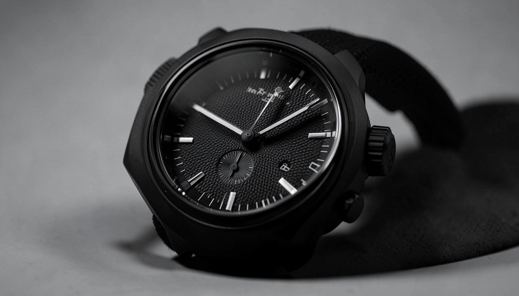Bold chronograph with a black ceramic case and textured dial, dramatic side lighting emphasizing its contours