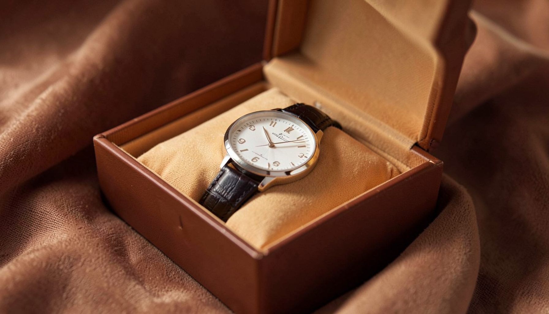 Elegant gift box with a classic dress watch, warm ambient tones and soft fabric textures