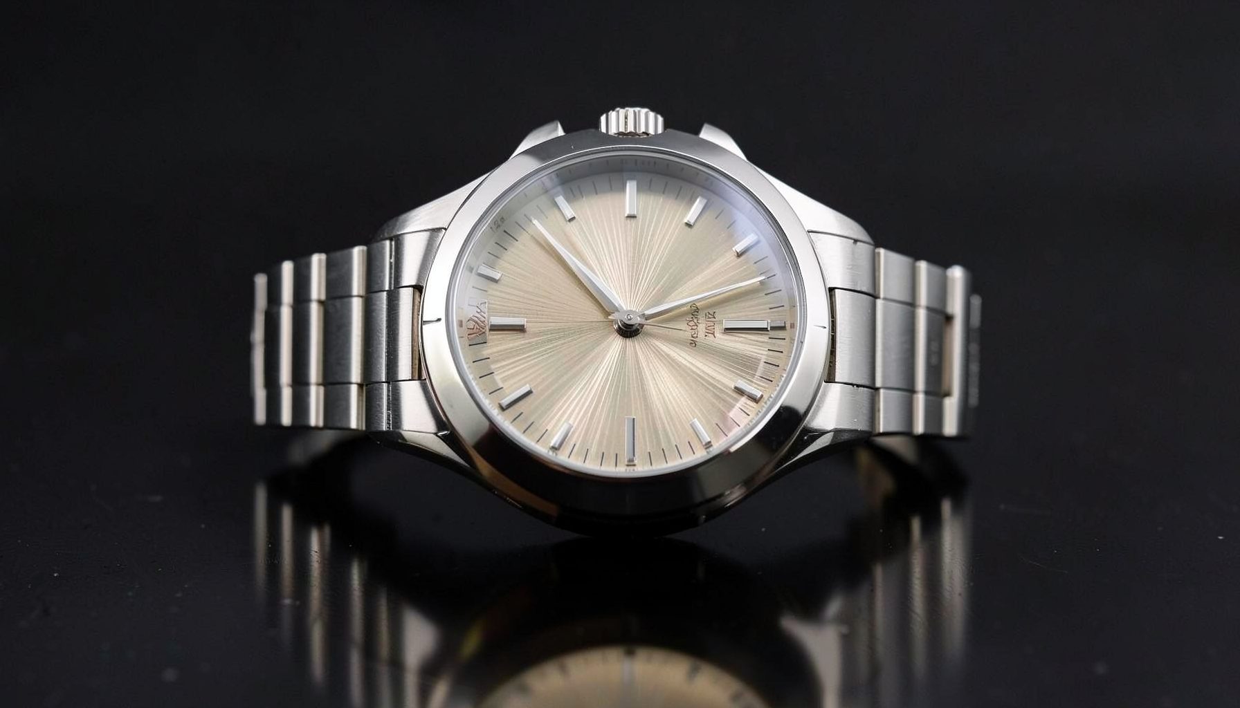 Luxury sports watch with an integrated bracelet and sunburst dial, photographed on a polished dark surface